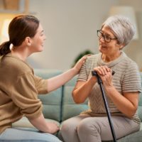 Lady with walking stick talks to female doctor in waiting room