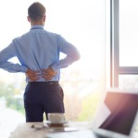 Man with chronic pain holds his lower back