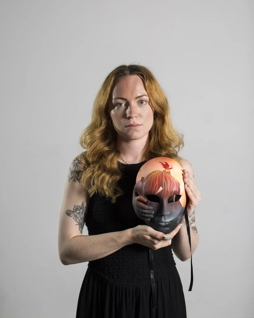 Curaleaf Clinic patient, Fran Taylor, holding her mask from the Pain Unmasked campaign